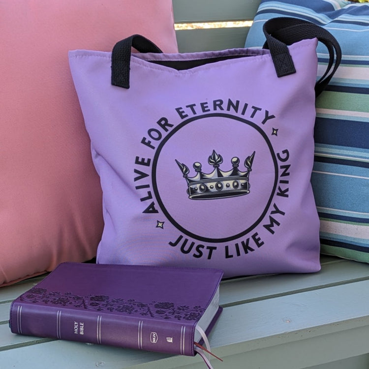 Purple tote bag with black text reading Alive for Eternity Just like my King around a crown graphic with a Bible next to the tote bag